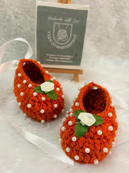 These vibrant orange booties are full of personality, decorated with pearls and a small white rose on top.
