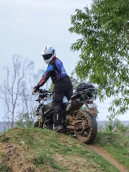 A rider in full gear navigates a grassy, uneven slope. Our Level 1 training helps you build the core confidence and balance needed for exactly these kinds of off-road challenges.
