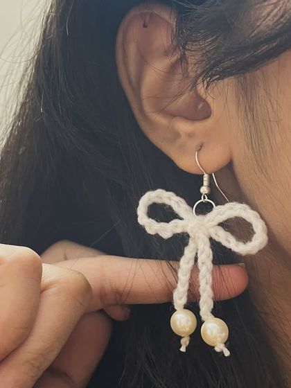These delicate white bow earrings with pearl drops are elegant and sweet. They are perfect for a soft, feminine look.