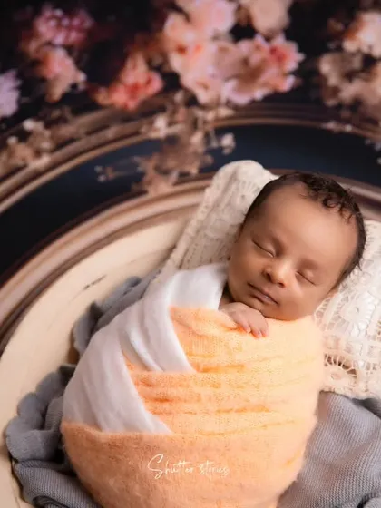 A close-up portrait from the frame setup, highlighting the baby's face and the texture of the lace pillow.