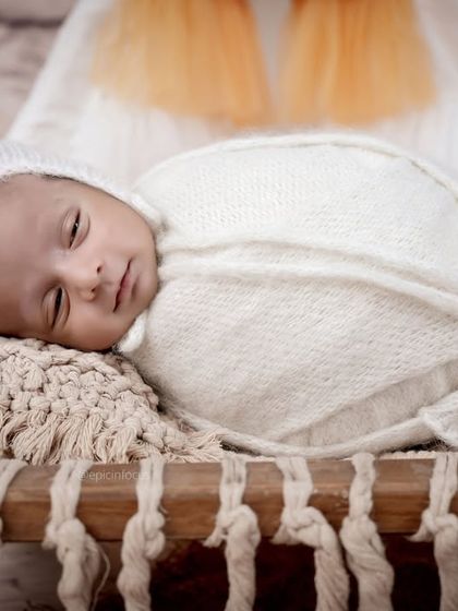 A detailed close-up of the baby's face, snug in a white wrap and bonnet, from our boho teepee session. The focus is always on your baby's comfort and cuteness.