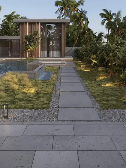A landscape design for a luxury residence in Delhi. This image shows the carefully planned walkway, flanked by ornamental grasses and leading towards a modern structure with a pool, all set within a verdant, tropical-inspired landscape.