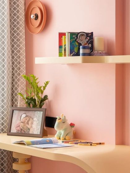 A close-up of the custom-designed study desk in the pink and blue kids' room. The curved form and soft colors make it an inviting space for homework and creative projects.