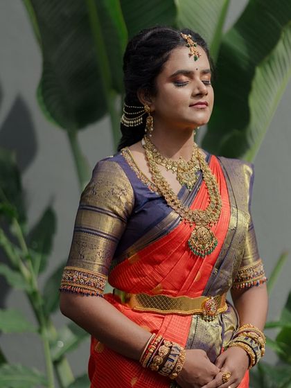 A serene portrait of the bride with her eyes closed. The focus is on the beautiful texture of her saree and the intricate details of her jewelry.