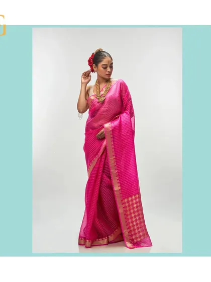 This vivid cerise silk organza saree is a celebration of color. The delicate gold zari checks and floral pallu make it a standout piece.