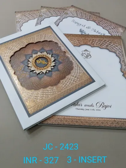 A premium boxed invitation with an intricate, multi-layered mandala design and a custom monogram. The white and bronze color scheme is elegant, and the set includes three inserts for your events.