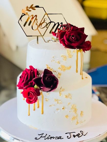A beautiful two-tier anniversary cake with red roses and gold drip accents.