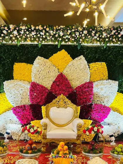 I can create grand, artistic floral backdrops for any occasion. This large lotus design, made entirely of fresh flowers in vibrant colors, provides a stunning and memorable stage for a Seemantham or engagement ceremony.