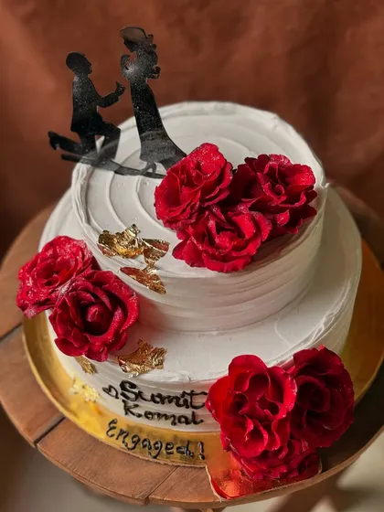 A different view of the two-tier engagement cake, showing the placement of the fresh roses and gold leaf details.