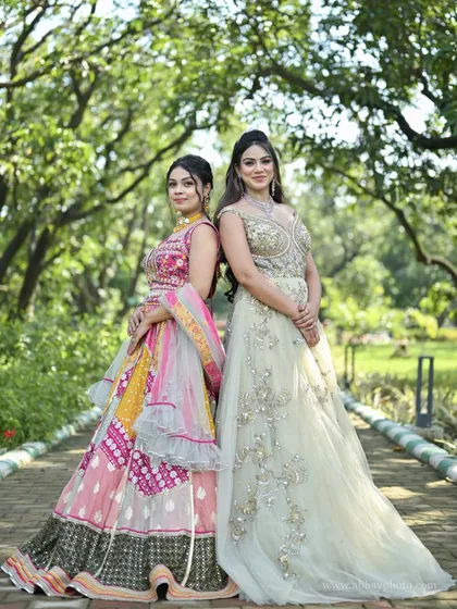 Two contrasting styles side-by-side. A vibrant pink and yellow patchwork lehenga stands next to an elegant pastel green gown, showcasing options for different tastes.