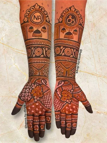 A royal-themed engagement design with the couple's initials 'NA' and a ring symbol set against palace-like domes. The arms are adorned with peacock and floral motifs.