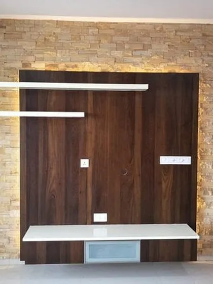 We combined a dark wood media unit with a rustic stone-cladding accent wall. The floating shelves and backlighting add a contemporary flair, creating a warm and inviting focal point in the living room.