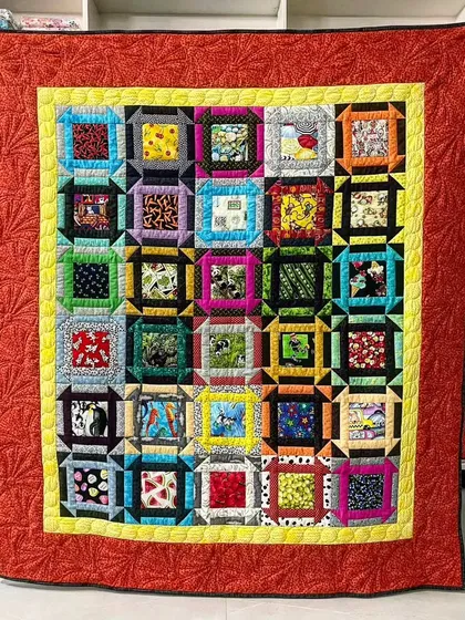 A "fussy cut" quilt where the center of each block features a specific motif from the fabric, framed by colorful borders.