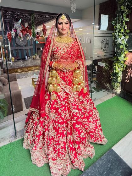 A full-length view of our stunning morning bride. The red lehenga with gold floral embroidery looks absolutely regal, and the makeup is designed to last throughout the day's ceremonies.
