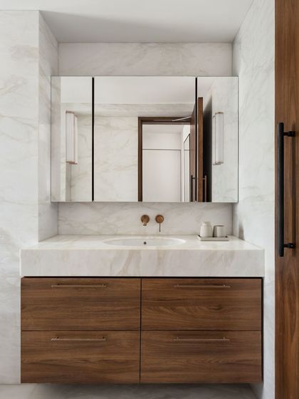 We used a beautiful white marble and a warm teak vanity in this bathroom at the West Coast Residence. The wall-mounted brass taps add a touch of timeless elegance.