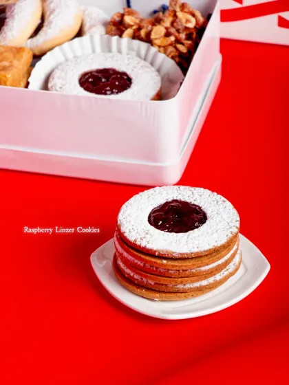 A stack of our Raspberry Linzer Cookies, with their signature jam-filled window and dusting of powdered sugar.