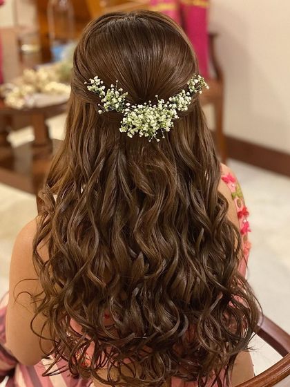 Messy curls with a half-up twist, adorned with baby's breath. This is a soft, romantic, and very popular choice for pre-wedding events like an engagement or Mehendi.