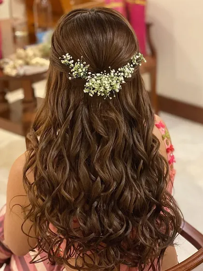Messy curls with a half-up twist, adorned with baby's breath. This is a soft, romantic, and very popular choice for pre-wedding events like an engagement or Mehendi.