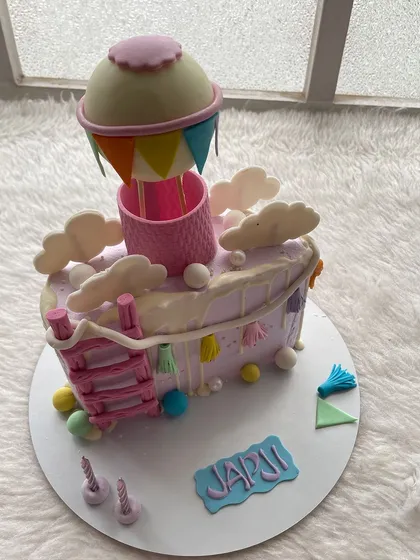 A hot air balloon-themed half-cake in pastel colors. It's a whimsical design for a six-month milestone.