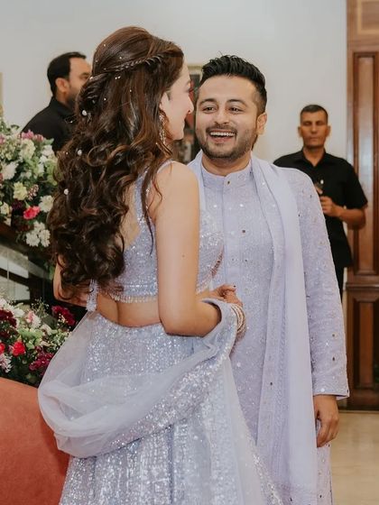 A candid moment between the couple. The bride's half-up style with soft waves and pearl accessories looks romantic and beautiful.