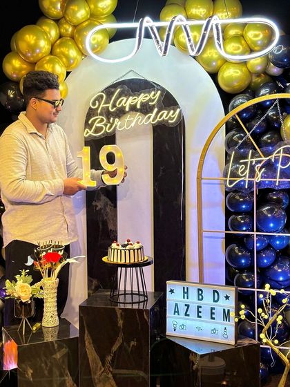 Holding up the "19" sign, the birthday boy is ready to celebrate his special day. The black marble pedestals and modern decor create a sleek and celebratory atmosphere for a milestone teen birthday.