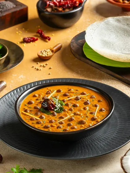 Kadala Curry, a black chickpea curry from Kerala, served with appam. The styling is authentic and traditional.