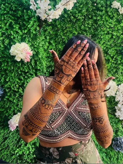 A happy bride showing off the dark, even stain of her full-arm mehndi.