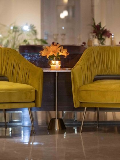A pair of modern accent chairs in mustard yellow velvet. The chairs feature a unique pleated design on the backrest and sleek metal legs, perfect for adding a pop of color and sophistication.