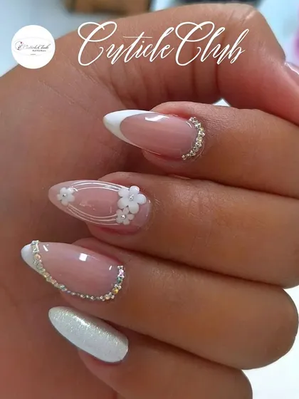 This is a perfect example of a modern bridal look. It features a classic French manicure on an almond nail shape, elevated with delicate 3D white flowers and a precise line of silver rhinestones at the cuticle for a touch of sparkle.