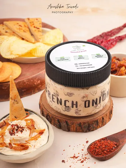 The French onion dip packaged for sale, styled with various chips and crackers. This is a great commercial shot that shows the product's versatility.