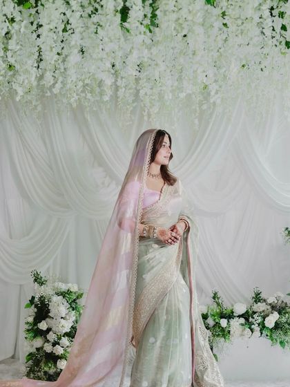 The bride, Hina Khan, looks ethereal against the backdrop of white florals and draped fabric. The decor was designed to complement her grace and the soft elegance of her attire.