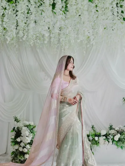 A vision in white, the bride stands against a backdrop of flowing white drapes and a ceiling of delicate wisteria. This celebrity wedding design focuses on creating a soft, dreamy, and ethereal atmosphere.
