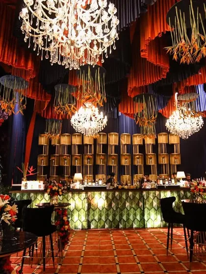 The magnificent bar was a central feature of the poker night. It featured a backlit geometric front, a towering back-shelf of lamps, and a ceiling of hanging florals and chandeliers.