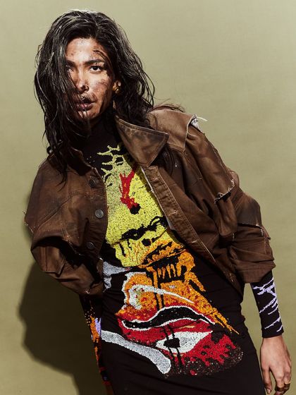 A model in a graphic, embellished dress and a deconstructed jacket, embodying the edgy spirit of the Huemn brand.