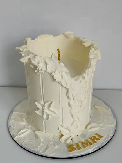 A special candle-inspired cake for a loyal client. This design features textured white frosting to resemble a melting candle, personalized with the name "Simri" in gold.
