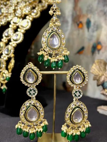 The complete accessory set to match our green Kundan necklace. This includes the beautifully crafted maang tikka and matching chandelier earrings.