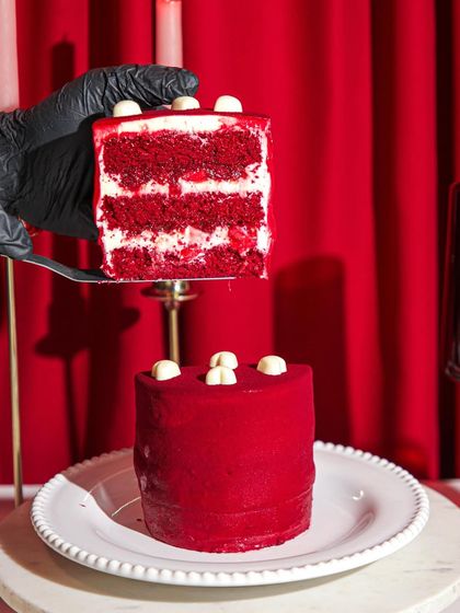A slice of our Valentine's special Red Hot Velvet Cake, revealing its vibrant red layers and creamy white frosting. It's love at first bite.