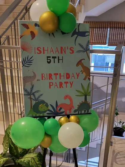 A custom welcome sign for Ishaan's 5th birthday party, decorated with dinosaur graphics and balloons.