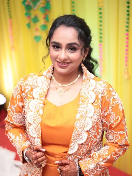 A confident and happy close-up. Her curly hair is styled in a chic ponytail, and her makeup is fresh and radiant.