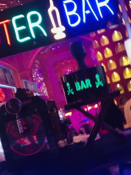 The neon signs create a fantastic atmosphere, especially for evening events. This 'Shooter Bar' setup is shown here with dramatic, colorful lighting.
