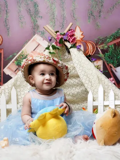 A cute toddler photoshoot with a garden tent theme. I use props like a picket fence, stuffed animals, and flowers to create a playful outdoor scene indoors.
