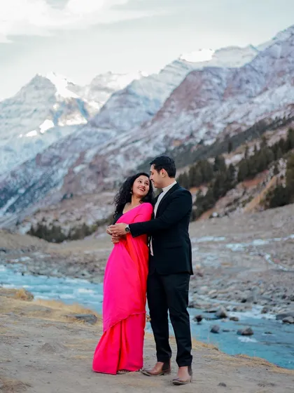A wide shot of the couple embracing, perfectly framed by the river and the grand mountains of Himachal.