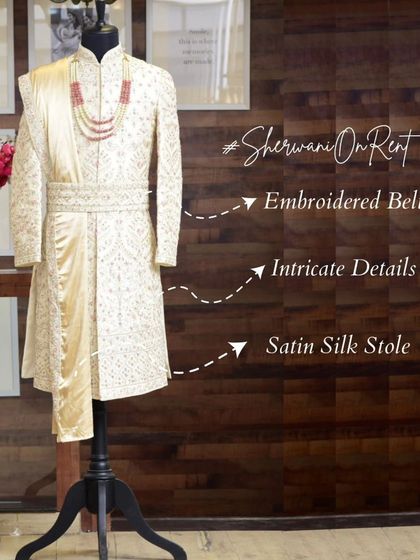 A detailed look at one of our premium rental sherwanis on a mannequin, highlighting the embroidered belt, intricate fabric details, and satin silk stole.