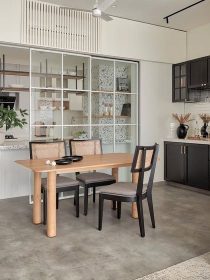 This open-plan layout seamlessly connects the kitchen, dining, and living areas. The design uses consistent flooring and a neutral color palette to create a spacious feel, while the sliding glass doors offer the flexibility to separate the kitchen when needed.