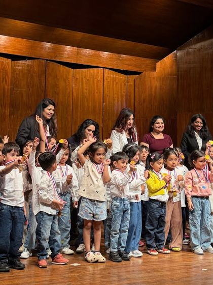 A joyful moment on stage as our youngest performers proudly show off their medals to the audience.