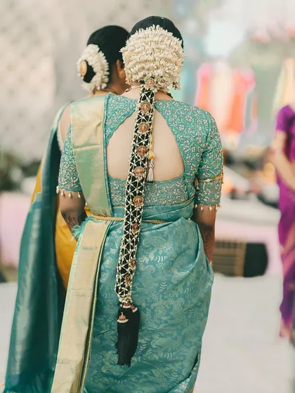 A detailed look at a traditional South Indian bridal hairstyle. This long braid is intricately decorated with gajra and golden accessories, a true statement piece for any bride.