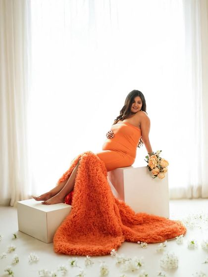 Another angle of the stunning orange gown, this time in a high-key setting with scattered flowers on the floor.