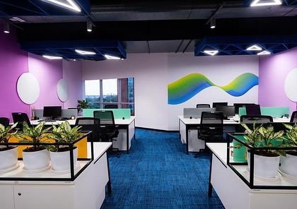 The use of bold colors and geometric shapes at the Tata Consumer Products office is balanced by the simple, repetitive placement of greenery, which adds a natural, calming element to the energetic space.