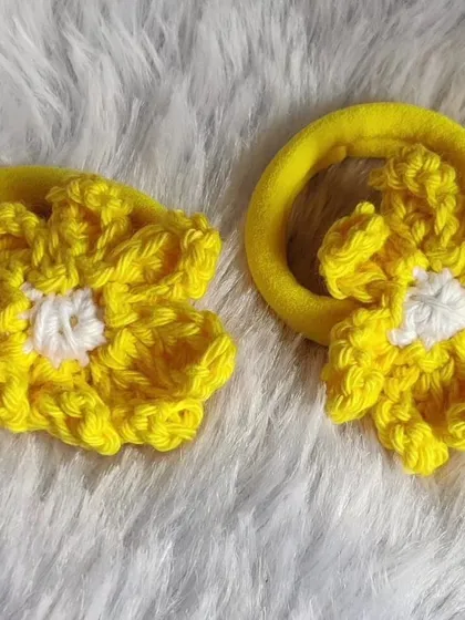 A pair of bright yellow floral scrunchies with a white center. Simple, cute, and perfect for everyday wear.