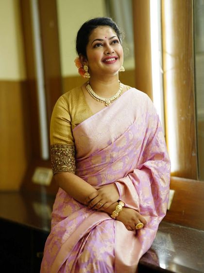 Priyanka Barve looking radiant and happy, seated by a window. The natural light beautifully illuminates her pastel saree.